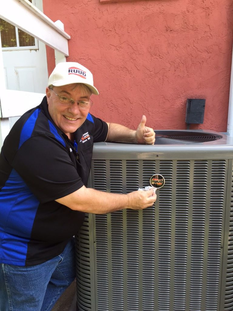 Blaine Aldrich, giving a thumbs up in front of an air conditioning unit outside.