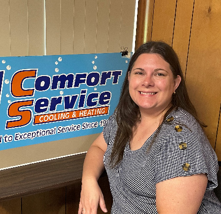 Christine Roland next to a board with the orange and blue Comfort Service logo.