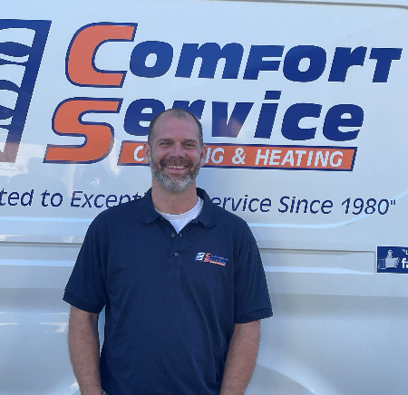 Garret Roland standing in front of a white van with the blue and orange Comfort Service logo.